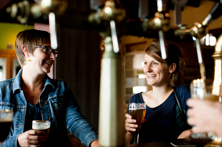 Twee vrouwen genieten van een Gouden Carolus in de brouwerij